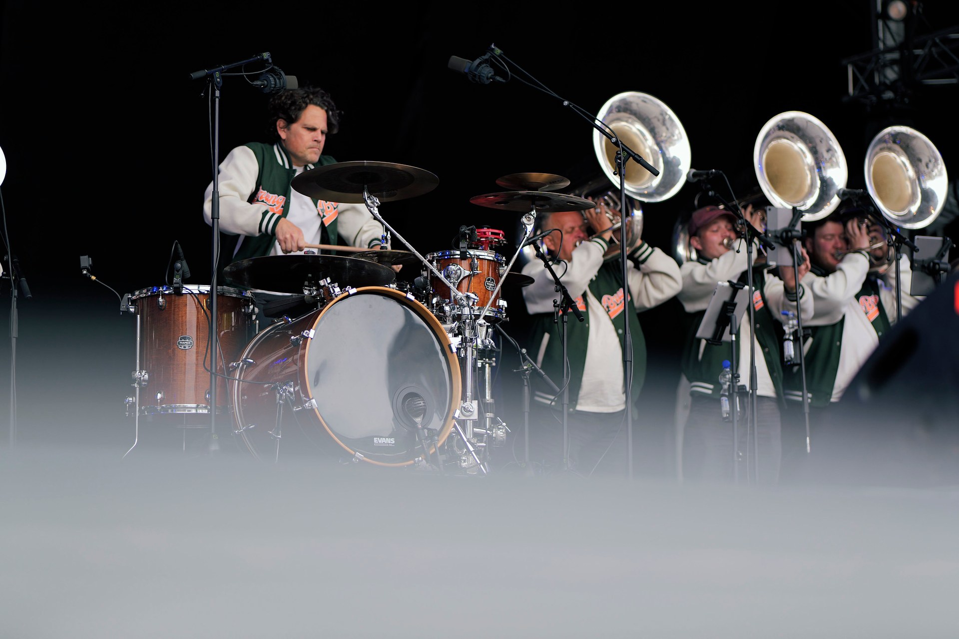 Orange Brass tijdens een avondoptreden, met percussie en sousafoons in de schijnwerpers