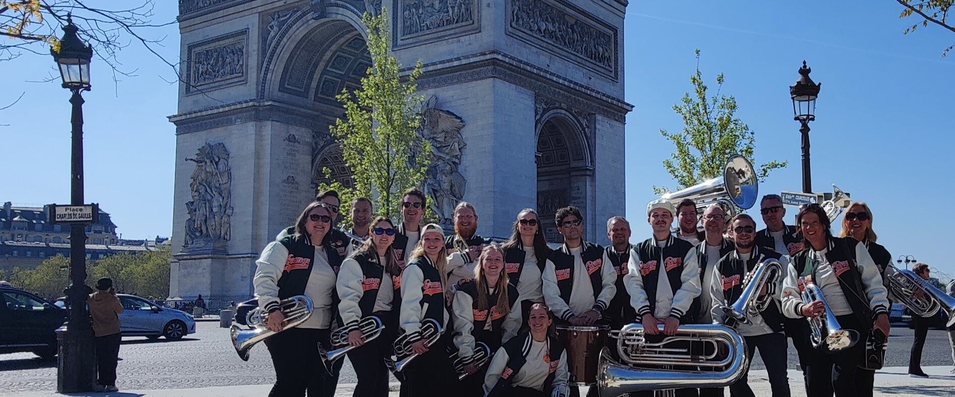 De muzikanten van Orange Brass in hun uniform bij de Arc de Triomphe in Parijs